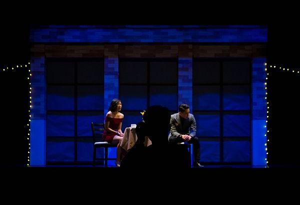 two people on a darkly lit stage